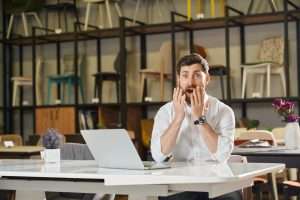 Shocked male retailer find out of profit results or career opportunities, while working in store.